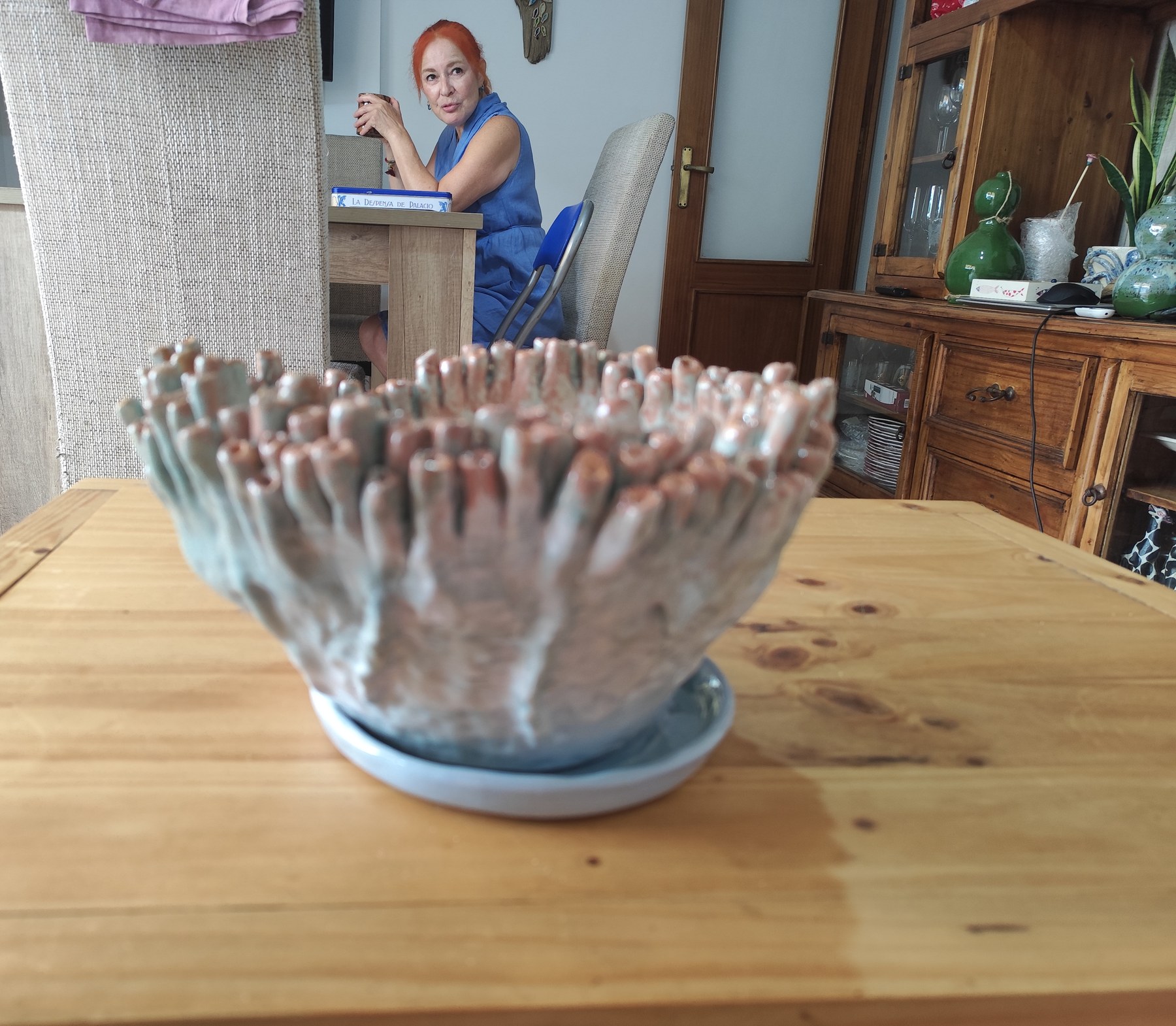 Maceta de corales sobre la mesa, con Irina Rocío al fondo